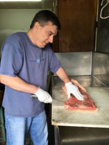 Dan carves strips of beef for wolves.